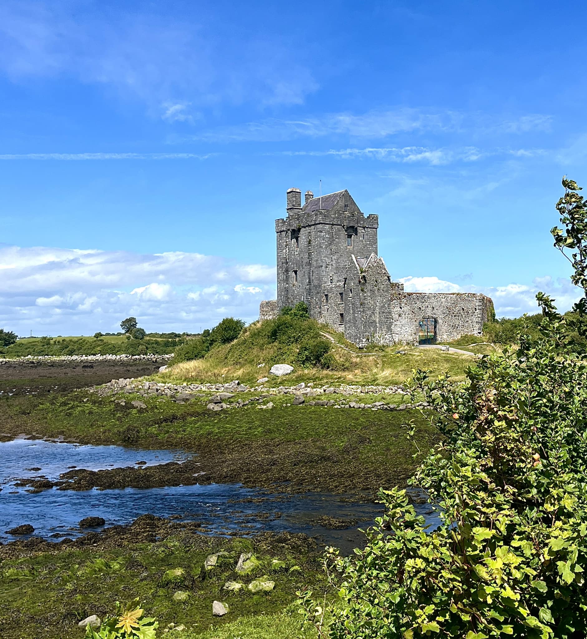 Doonagore Castle stands prominently against a bright blue sky,
