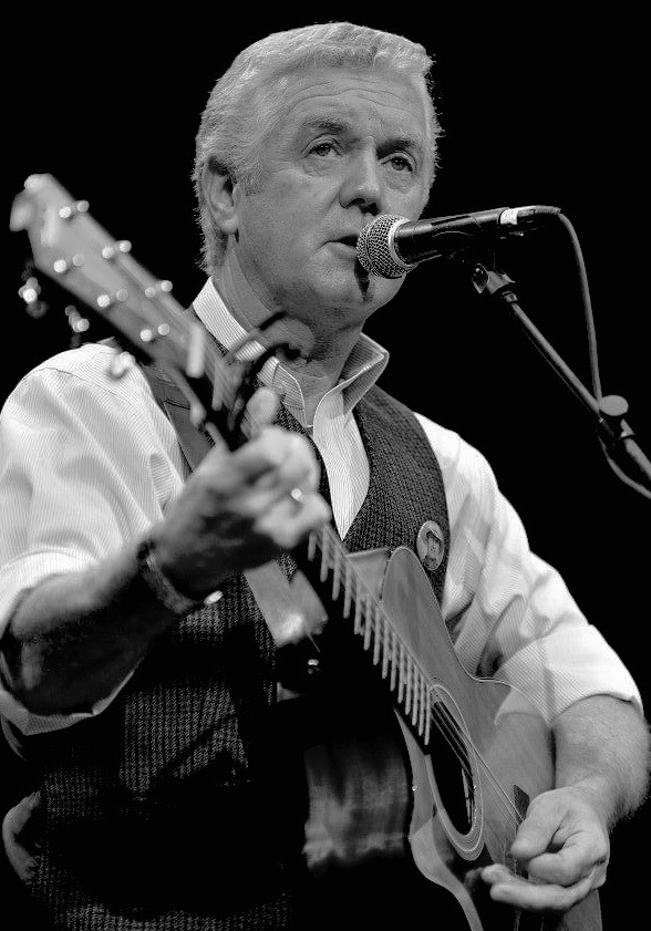 Musician performing with an acoustic guitar and microphone,